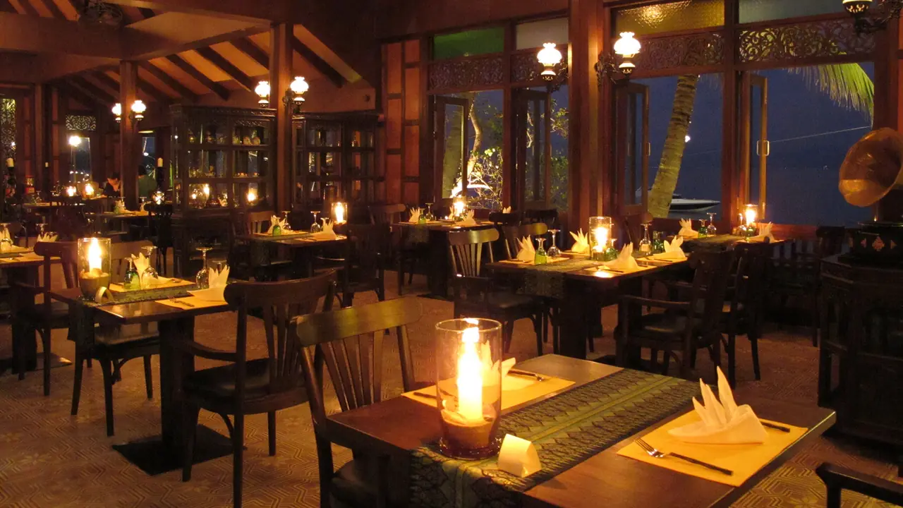 Inside the teak hall at night, candles on silk table runners