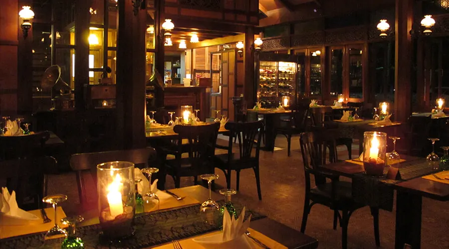 Candles on the tables inside the hall at night, lamps and glass cabinets behind
