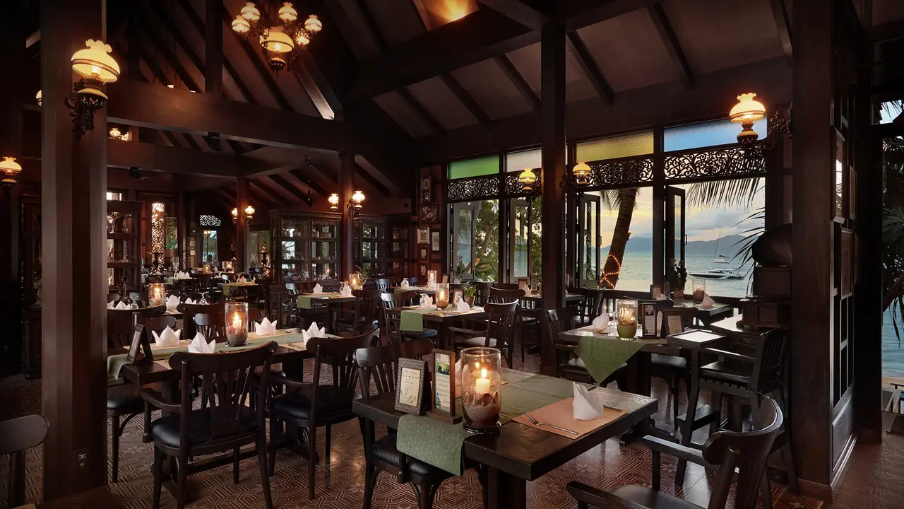 Inside the teak hall by day, lanterns, carved windows onto the beach