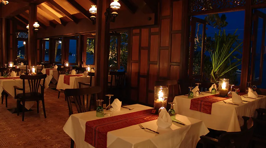 The hall at night, white tables with red runners and the blue sea outside