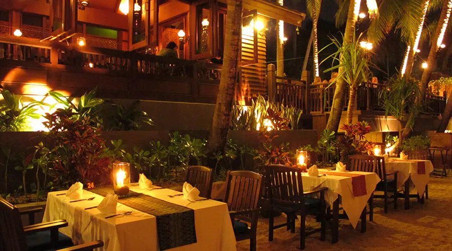 Candlelit tables on the garden terrace at night, under lit palms