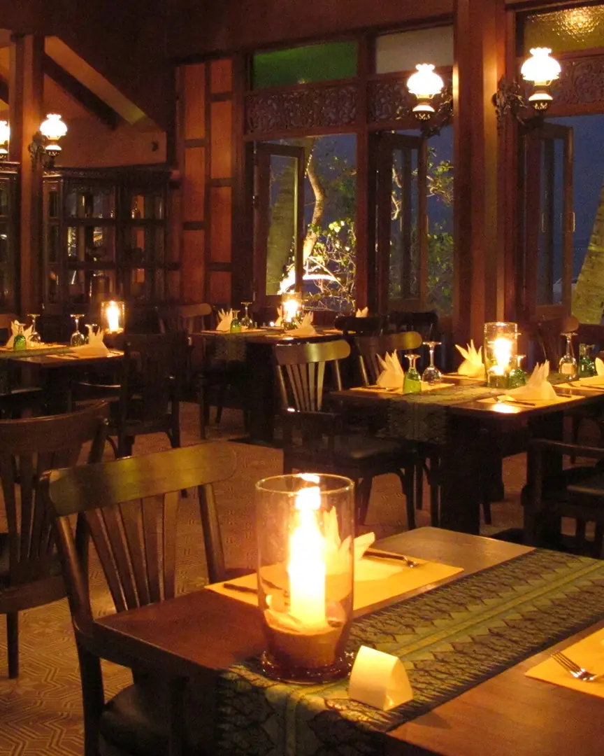 Inside the teak hall at night, candles on silk table runners